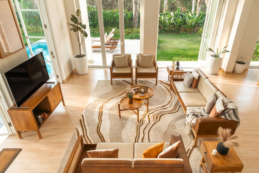Luxury villa living room with large windows overlooking a lush garden and private swimming pool